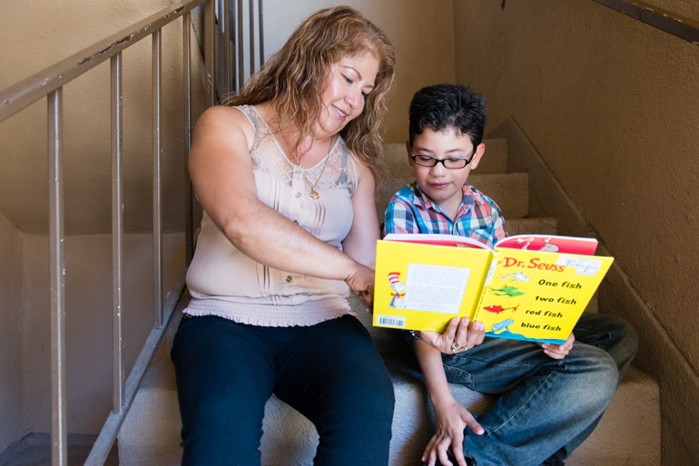 Torres reads to her U.S. born son Esau Rodriguez, 7, on the stairs of their apartment. DAPA, or Deferred Action for Parents of Americans and Lawful Permanent Residents, would allow undocumented adults like Torres to seek protection from deportation if they lived in the country continuously since 2010 and had a U.S. born child. (Heidi de Marco/CHL)