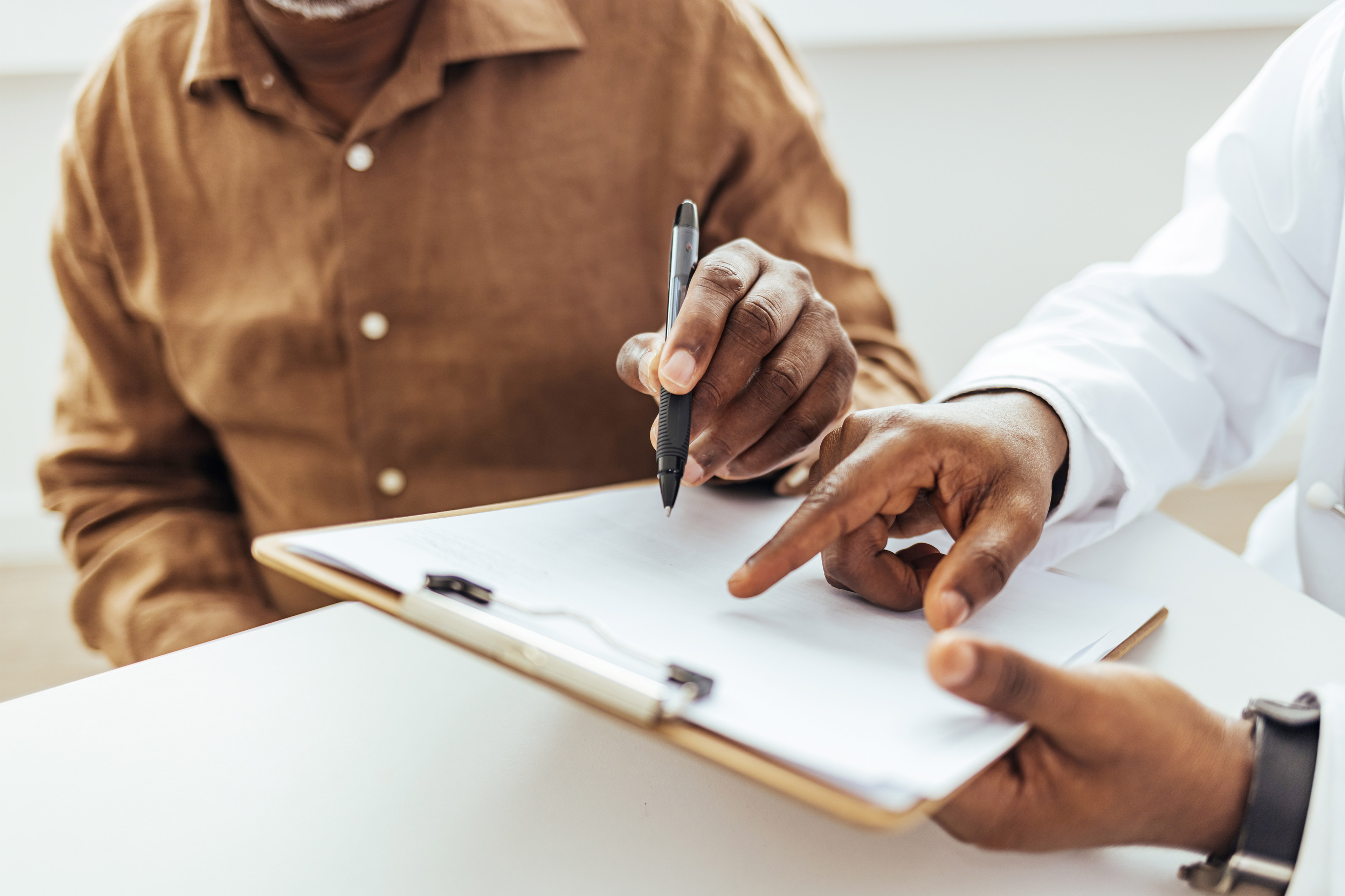 A photo of a doctor showing a patient a medical form on a clipboard.