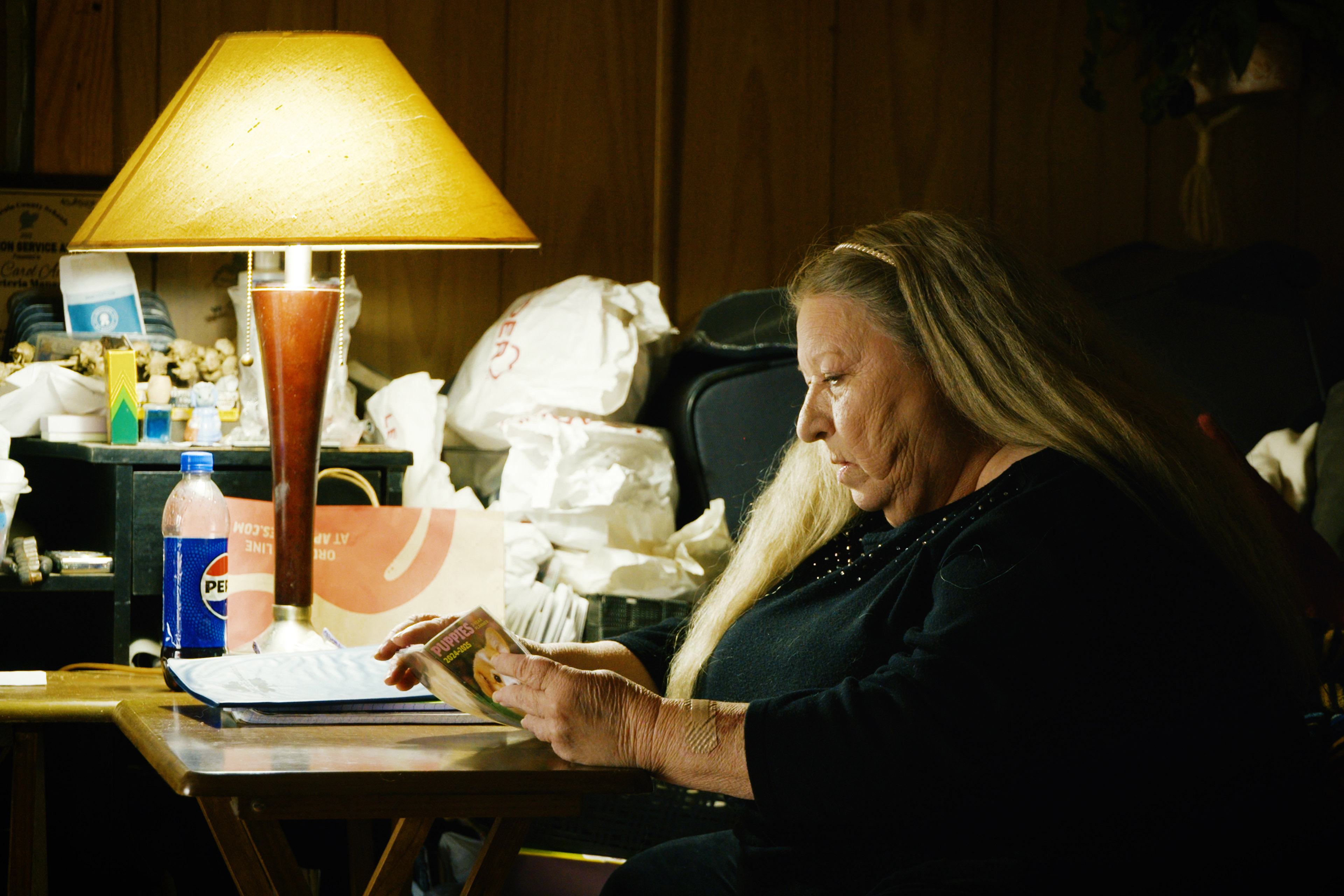 A woman wearing a black sweater looks through a small book at a table