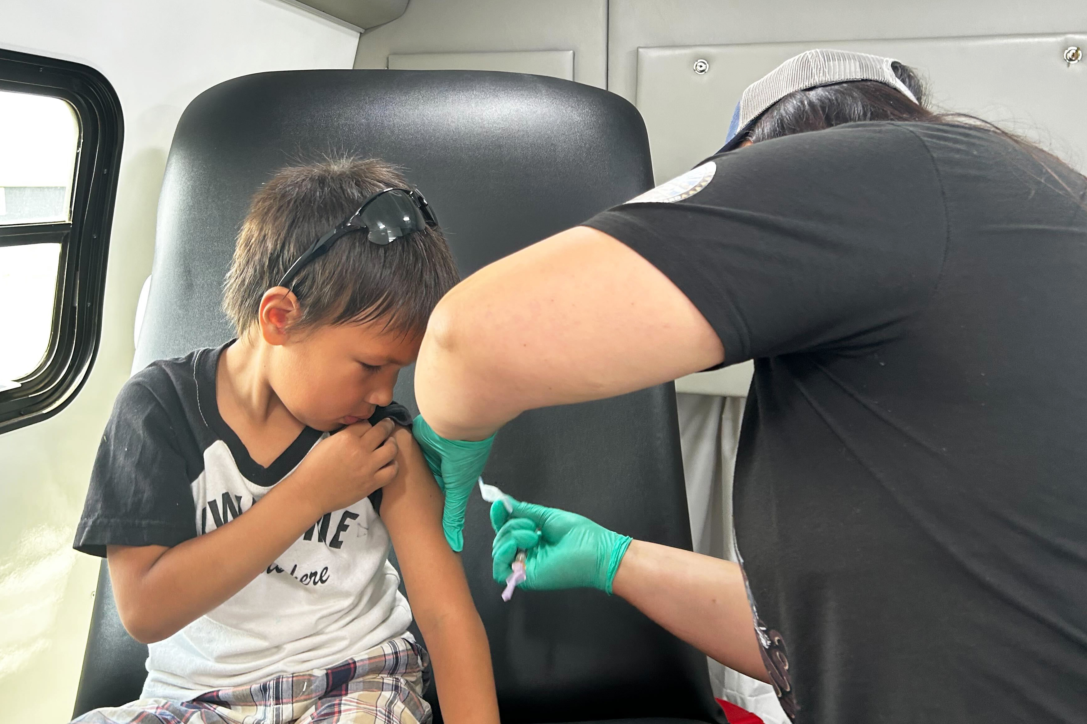 A photo of a medical professional giving a young boy a measles vaccine.