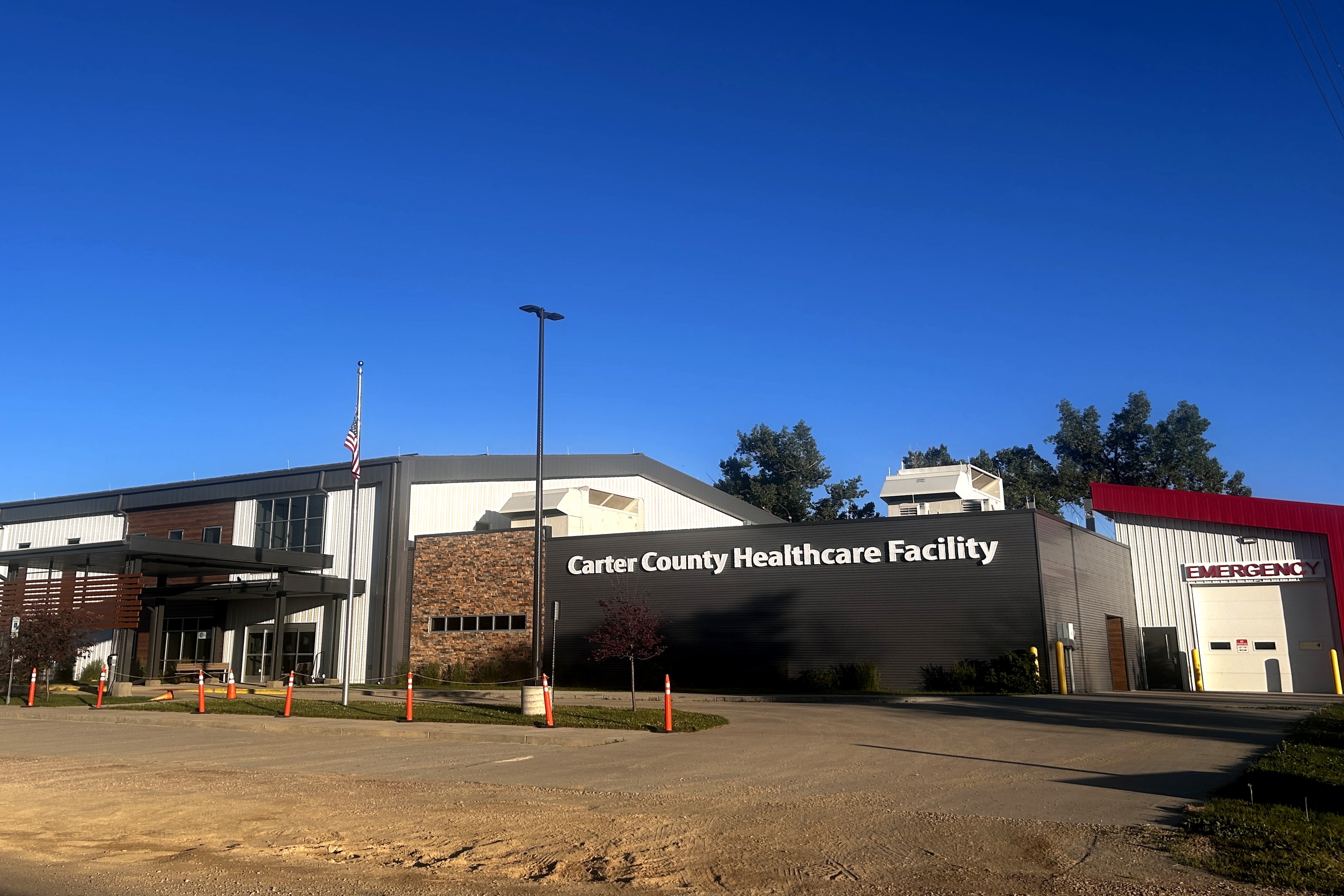 The exterior of a rural hospital with a sign that reads 'Carter County Healthcare Facility'