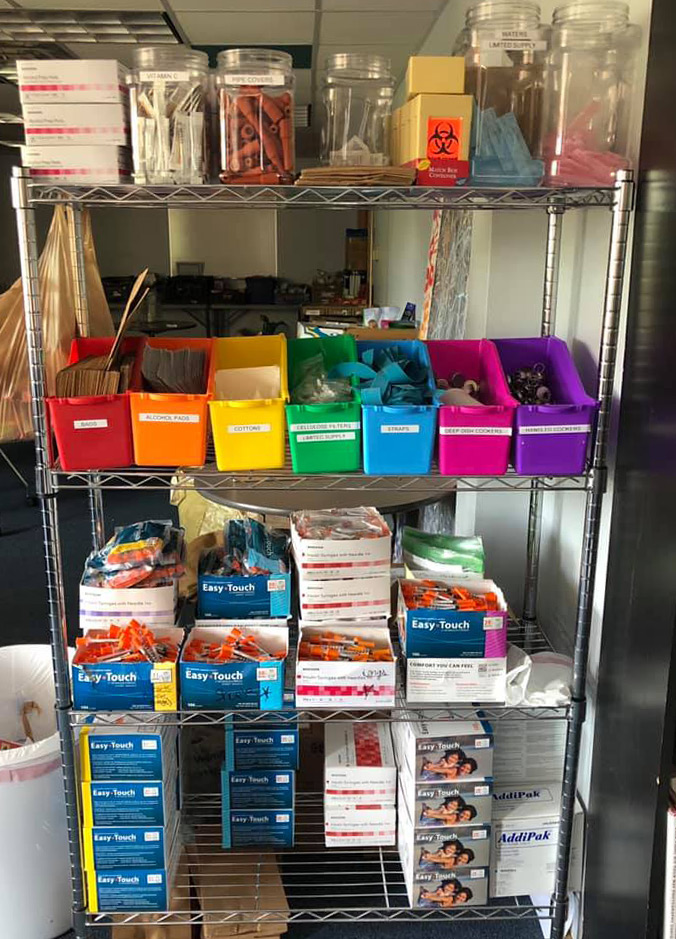 A photo of a display rack of sterile needles, alcohol pads, arm straps, cotton swabs, etc.