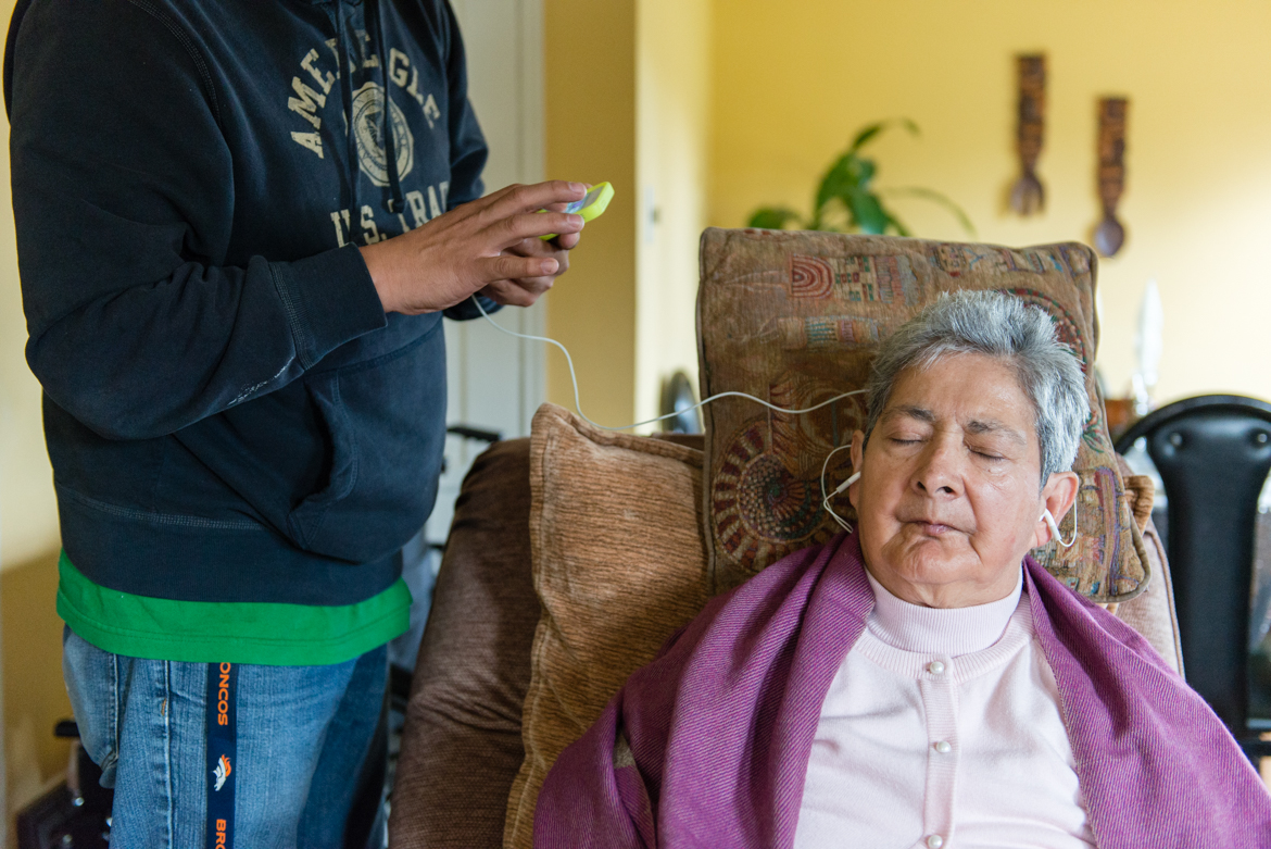 Mario Yanes, 48, uses an IPOD to play music for his mother, Blanca Rose Rivera. (Heidi de Marco/California Healthline)