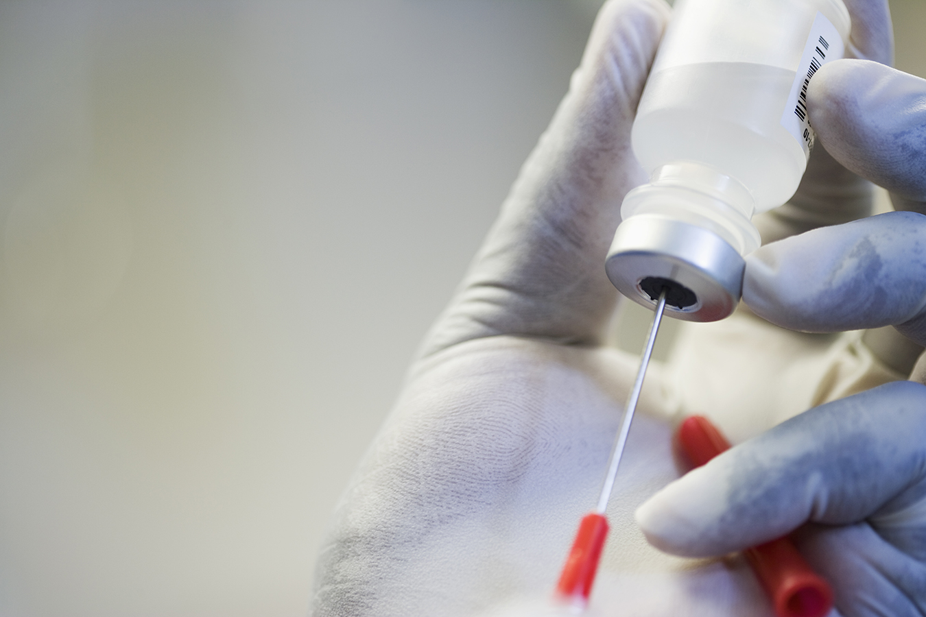 Close up of hand in rubber glove filling syringe