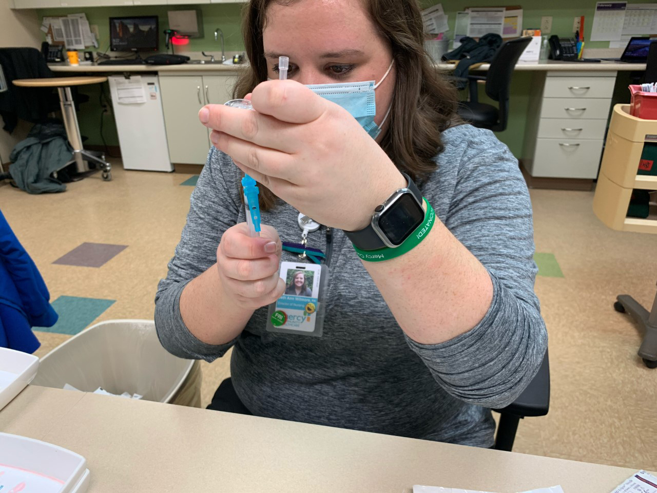 Beth Ann Wilmore checks a vaccine vial at her community health center