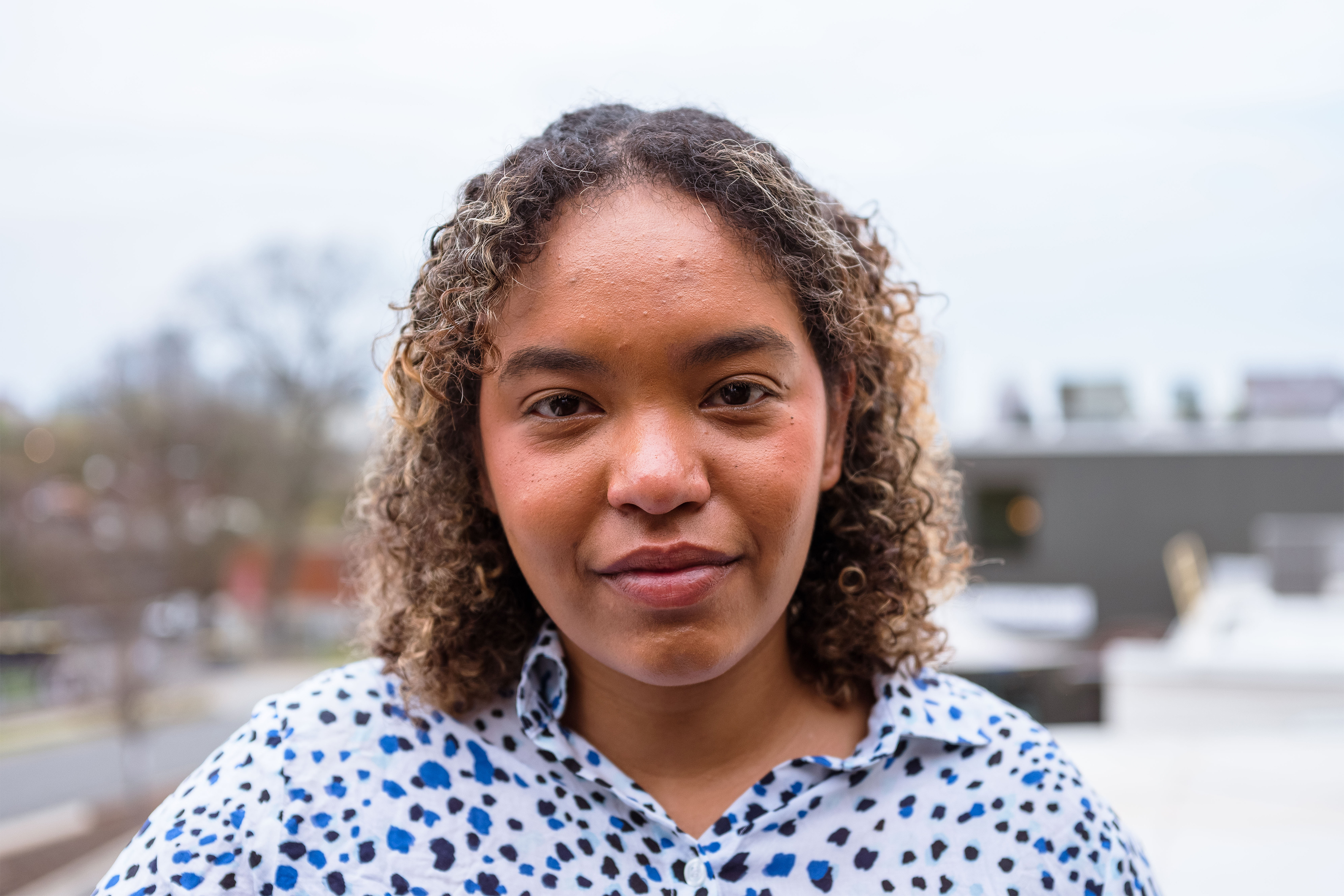 Daisha Williams is seen in front a blurred backdrop of buildings and roads.