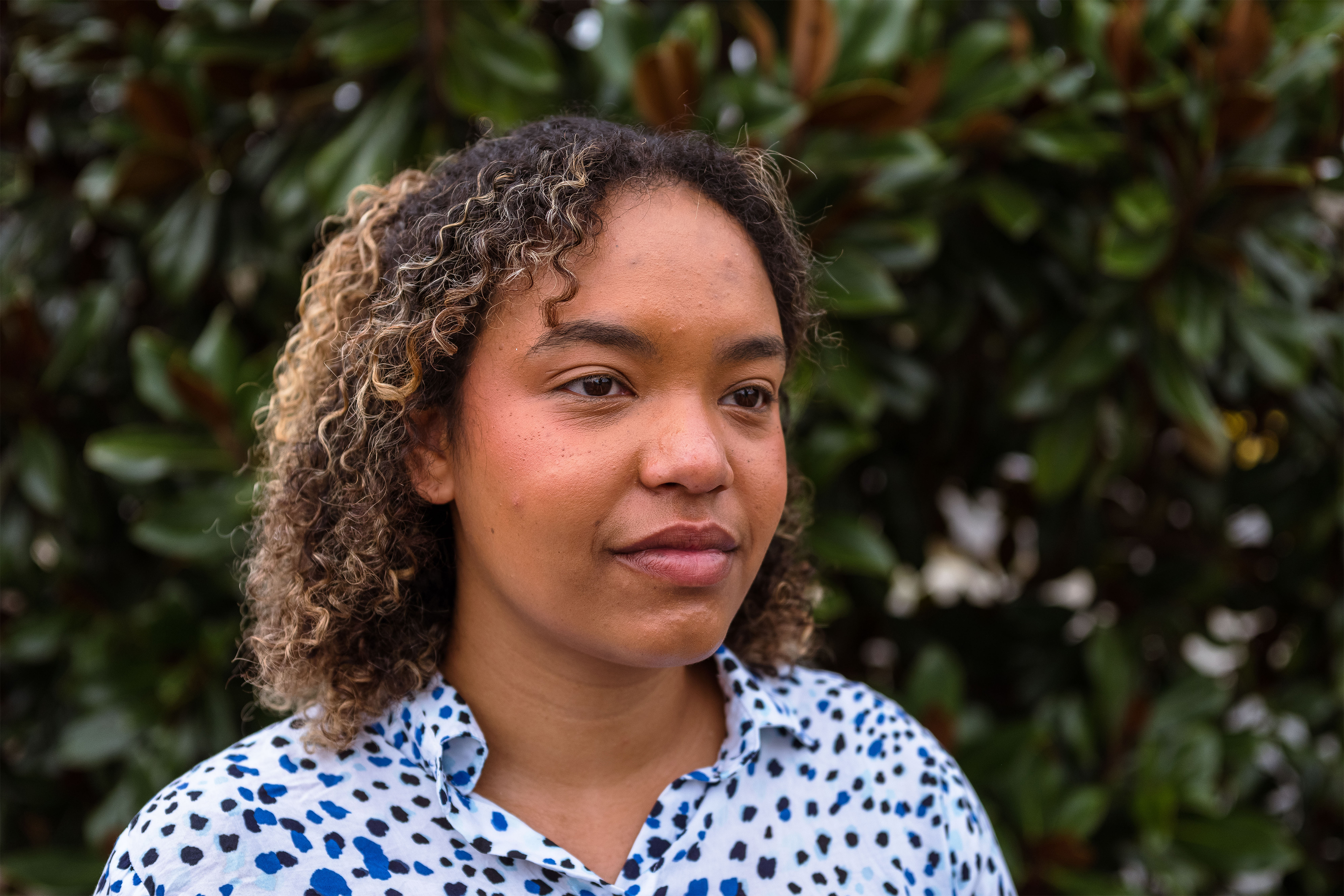 Daisha Williams is seen standing in front of a green bush.