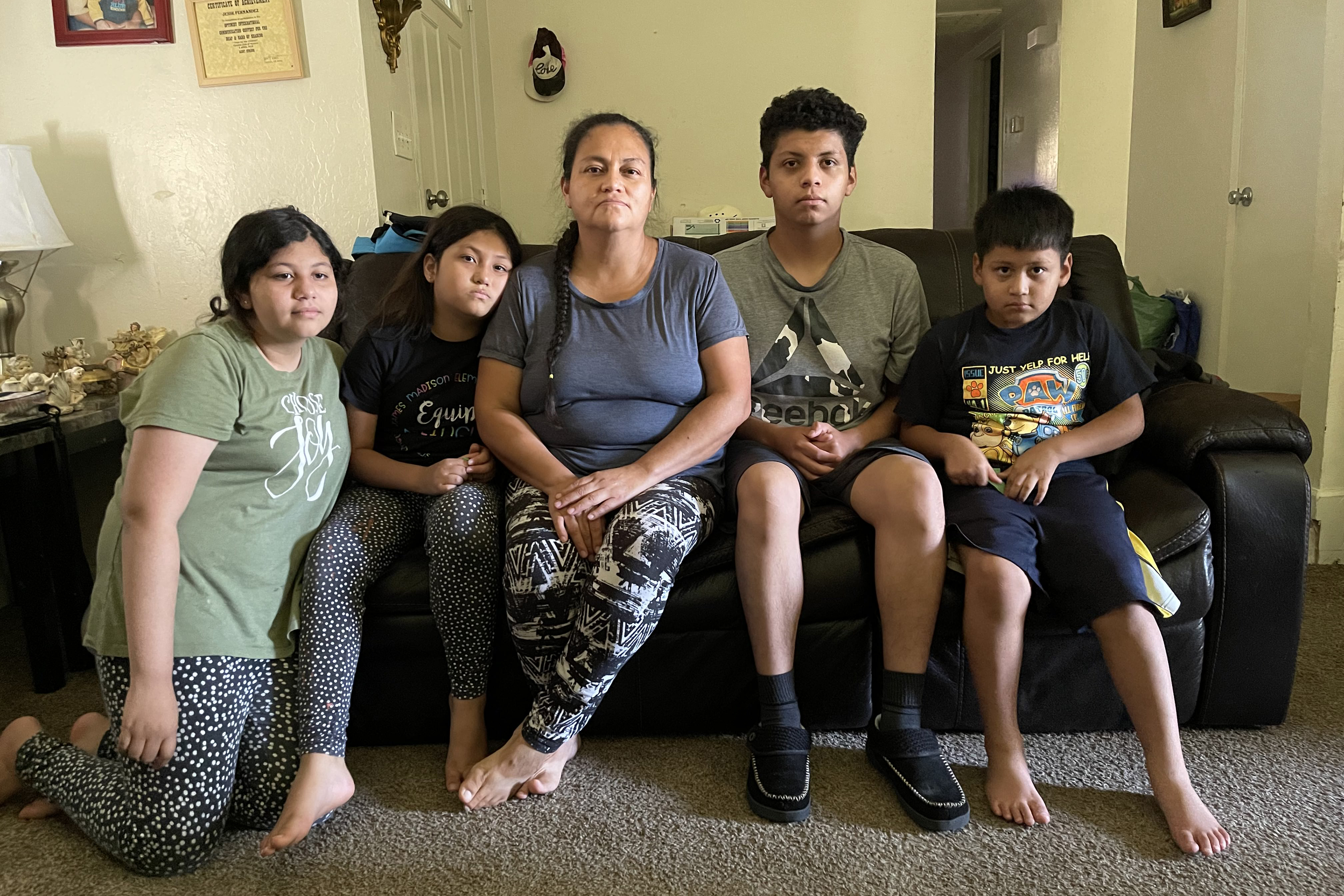 A woman and four children sit on a couch.