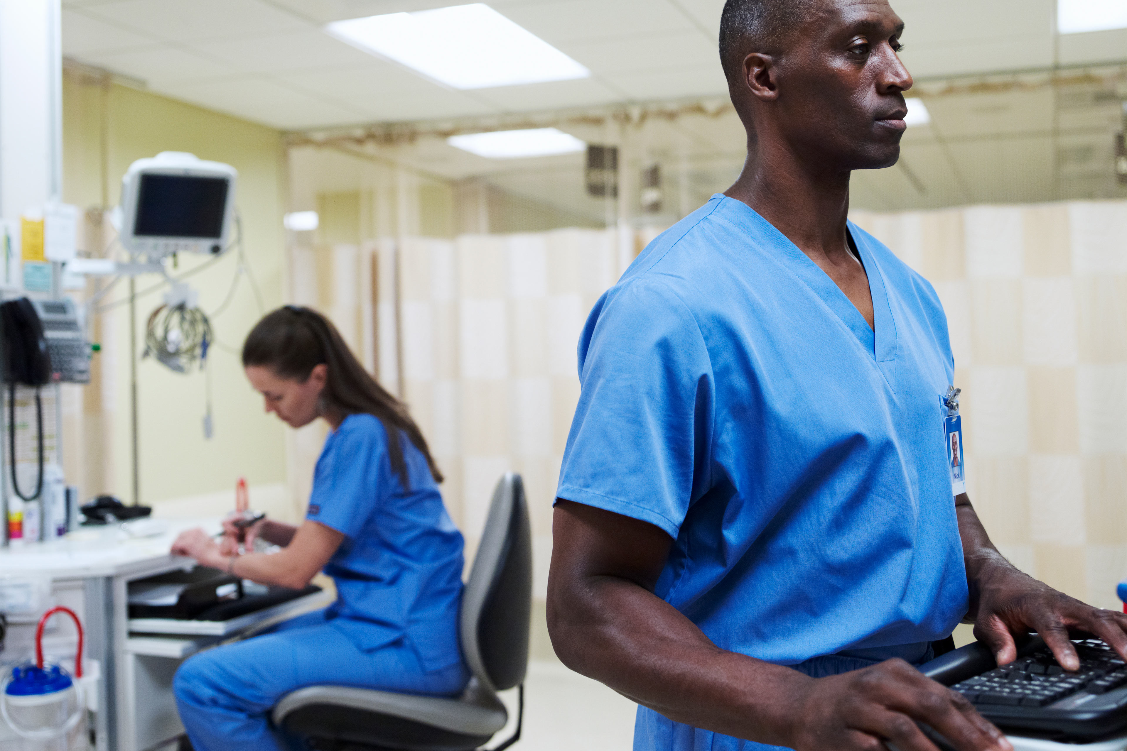 A photo shows a female and male nurse working at computers inside a hospital.