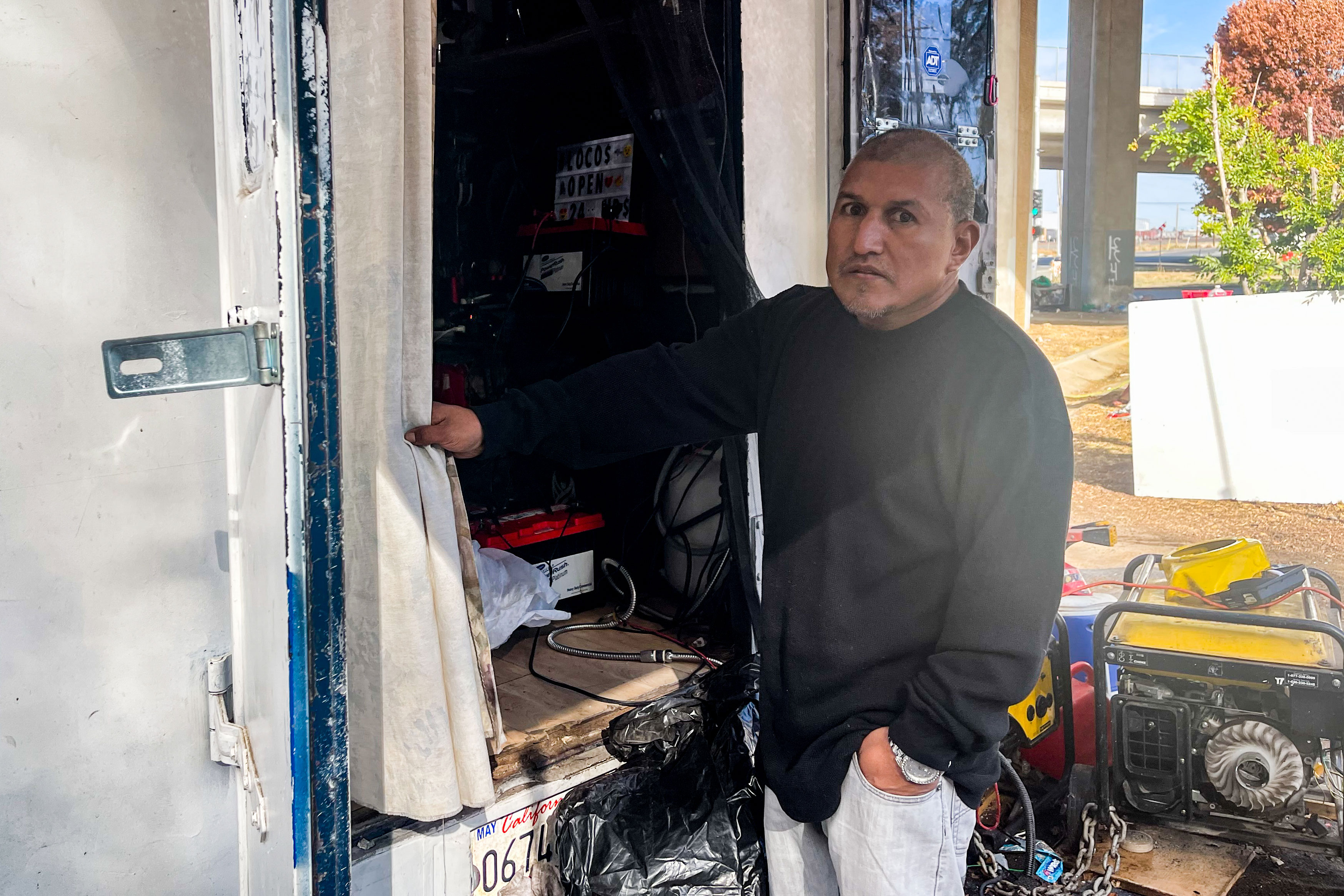 A photo shows Joe Guzman sitting outside in the encampment where he lives.