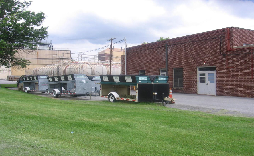 The exterior of a low brick building with three trailers in front of it.