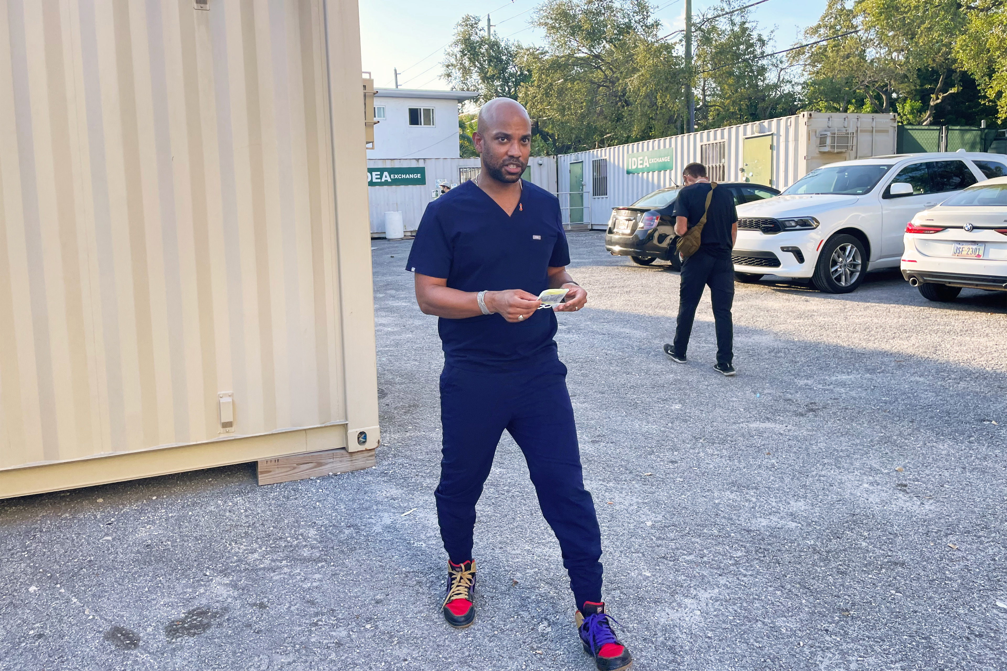 A photo a man in scrubs standing outside.