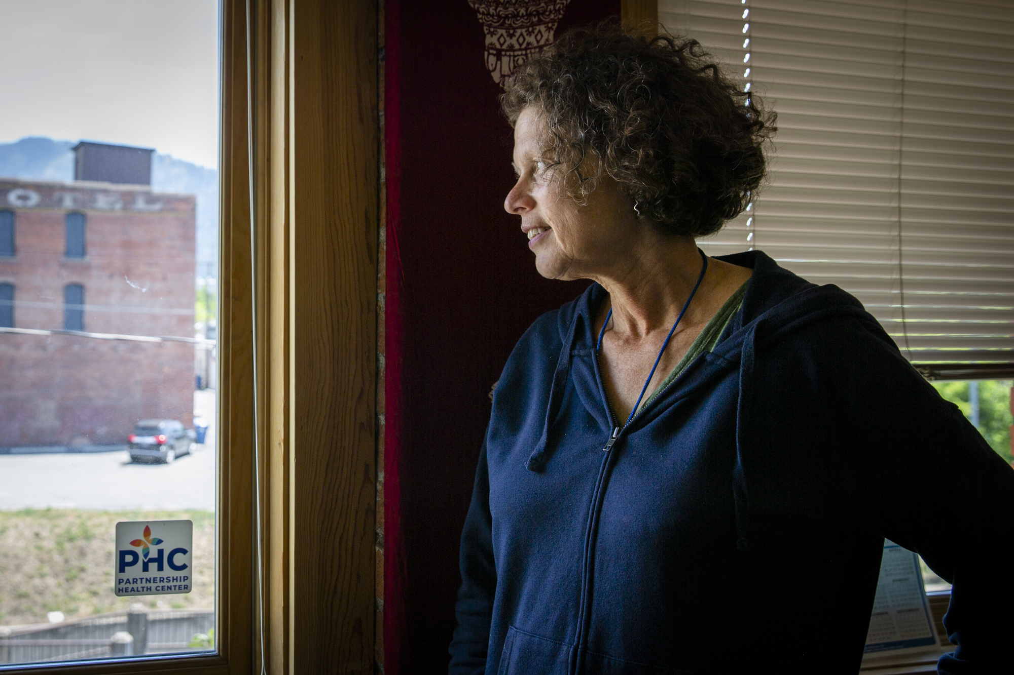 A photo of a woman looking out a window indoors.