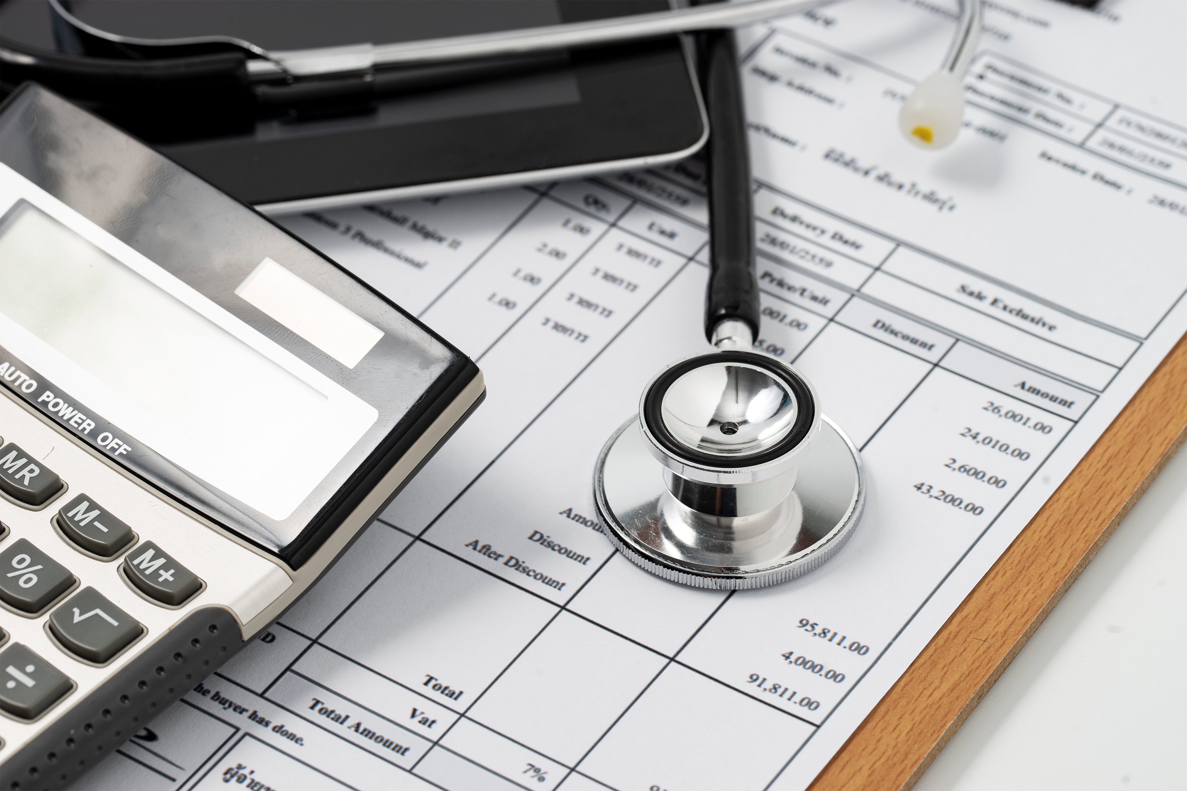 A photo of medical bills, a stethoscope, and a calculator.