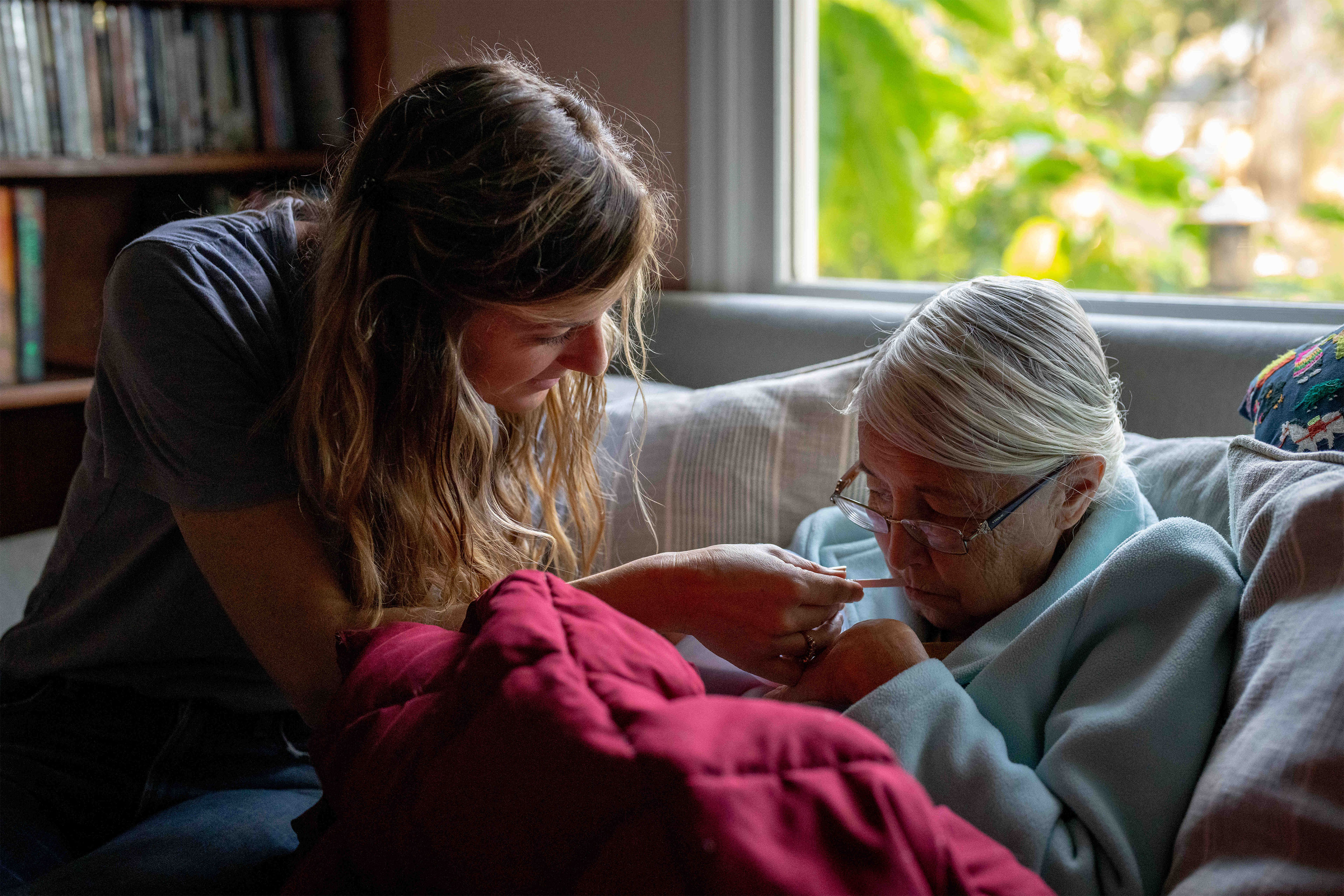A photo of a caretaker aiding an elderly woman.