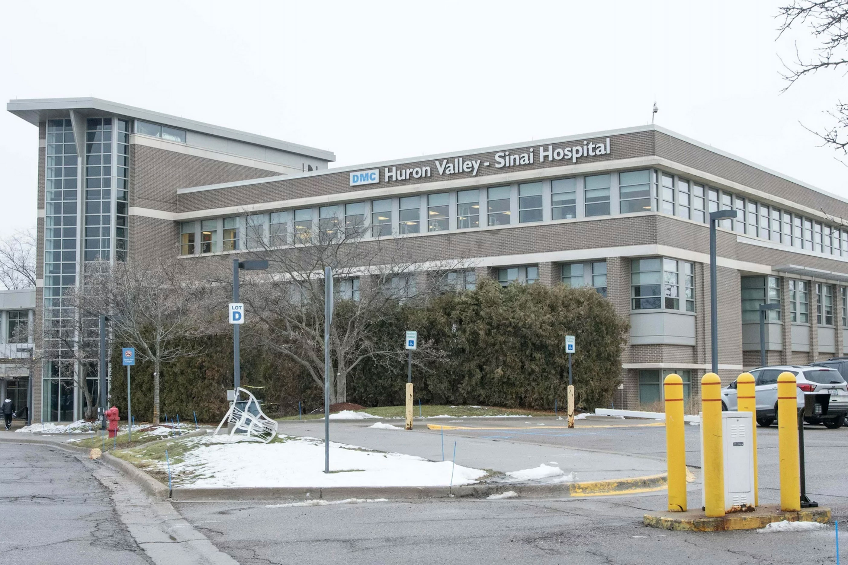 A exterior shot of a building from the adjacent parking lot. Words on the side of the building read "DMC Huron Valley - Sinai Hospital".
