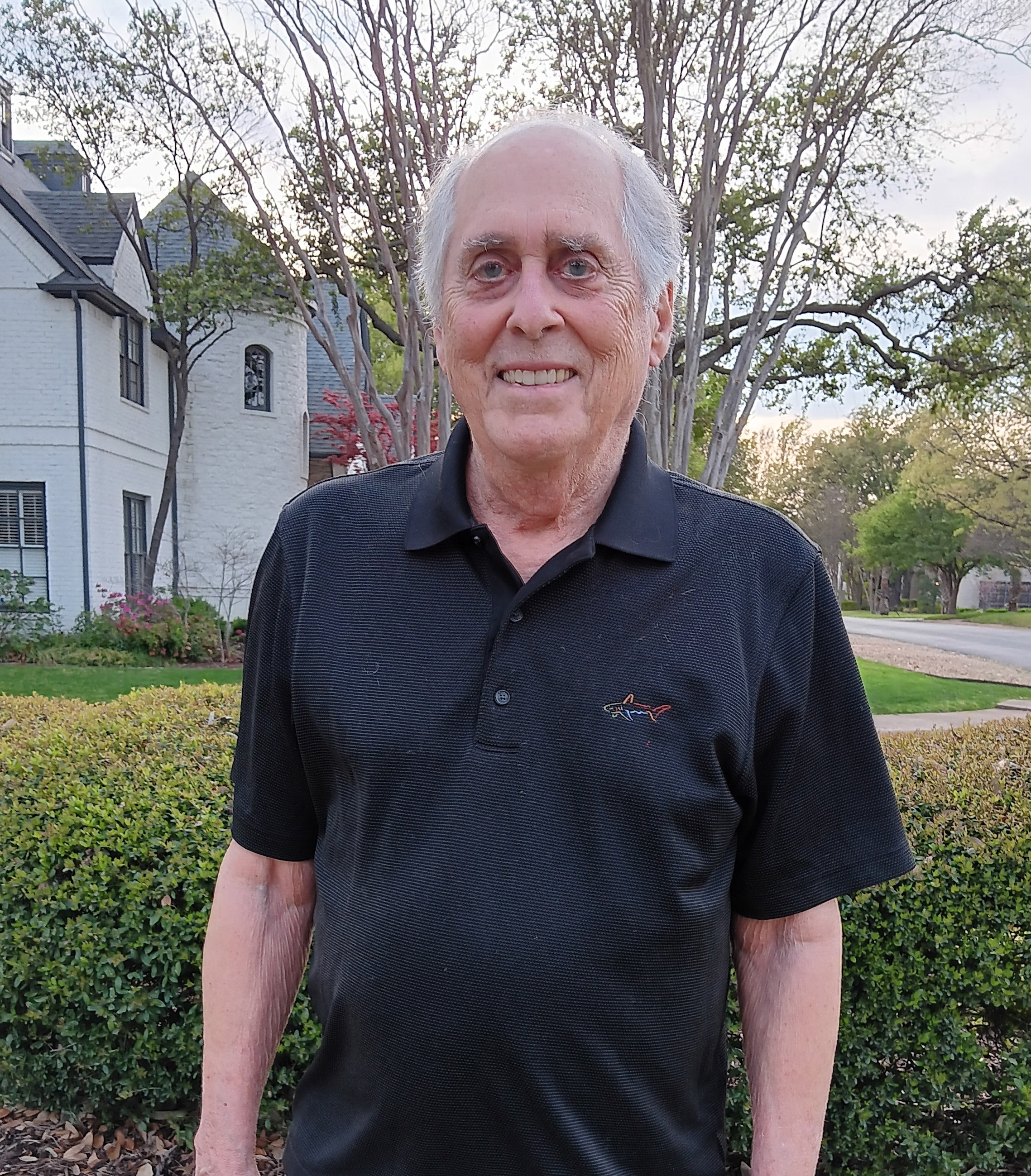 A photo of an older man standing for a photo outside.