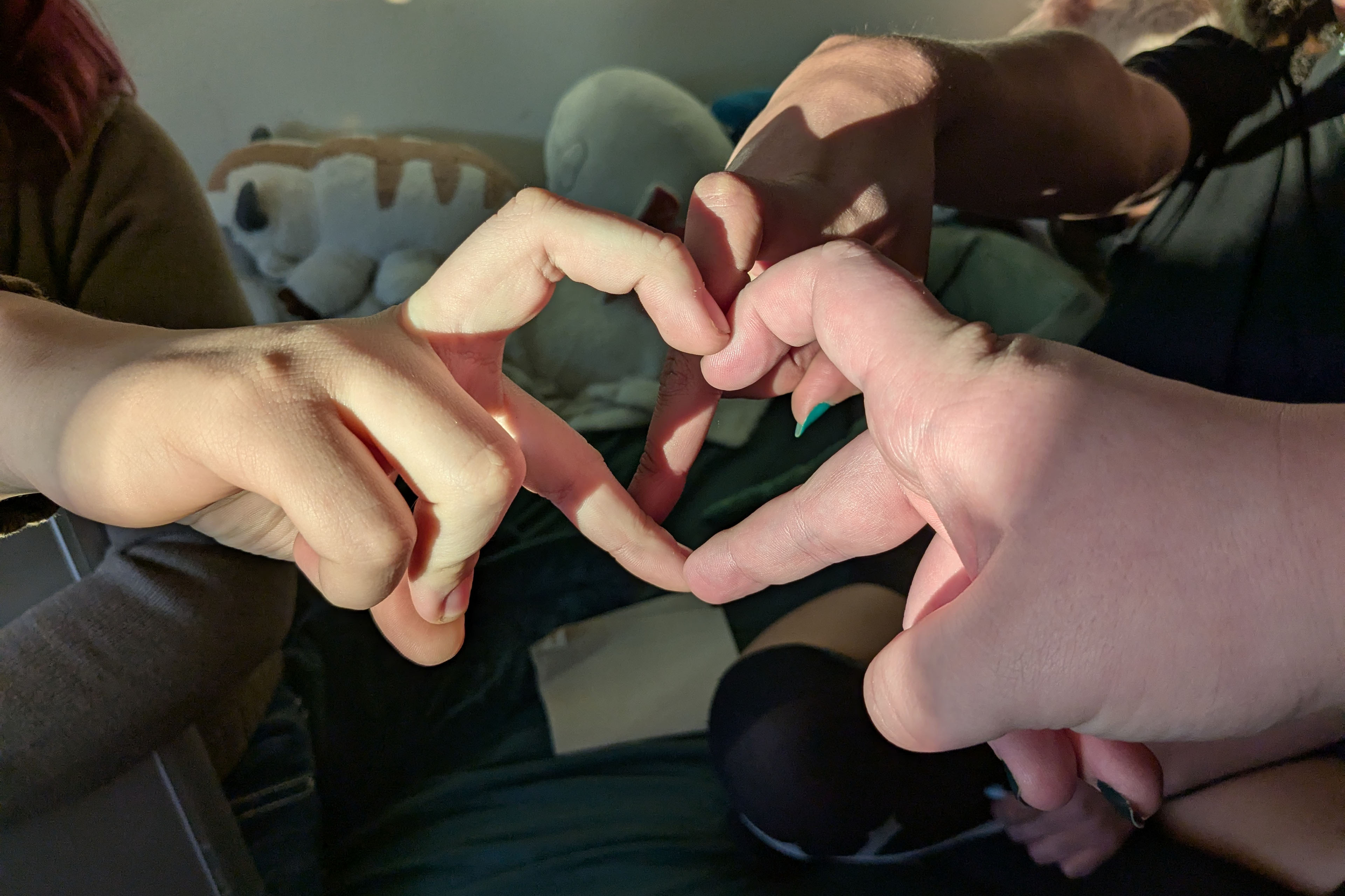 Three hands link together to make a heart shape.