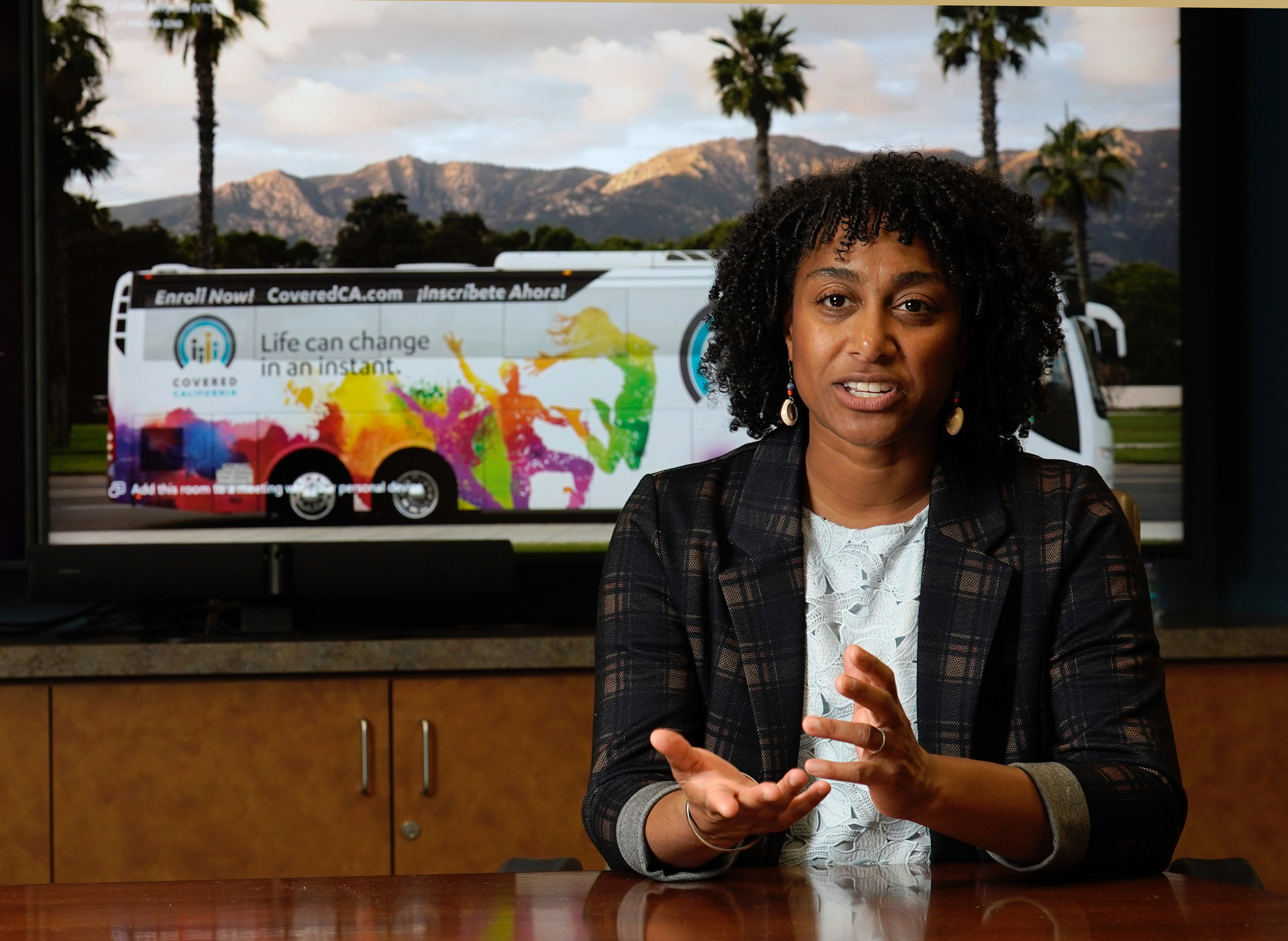 A photo of Monica Soni sitting in a conference room, speaking to someone out of frame.