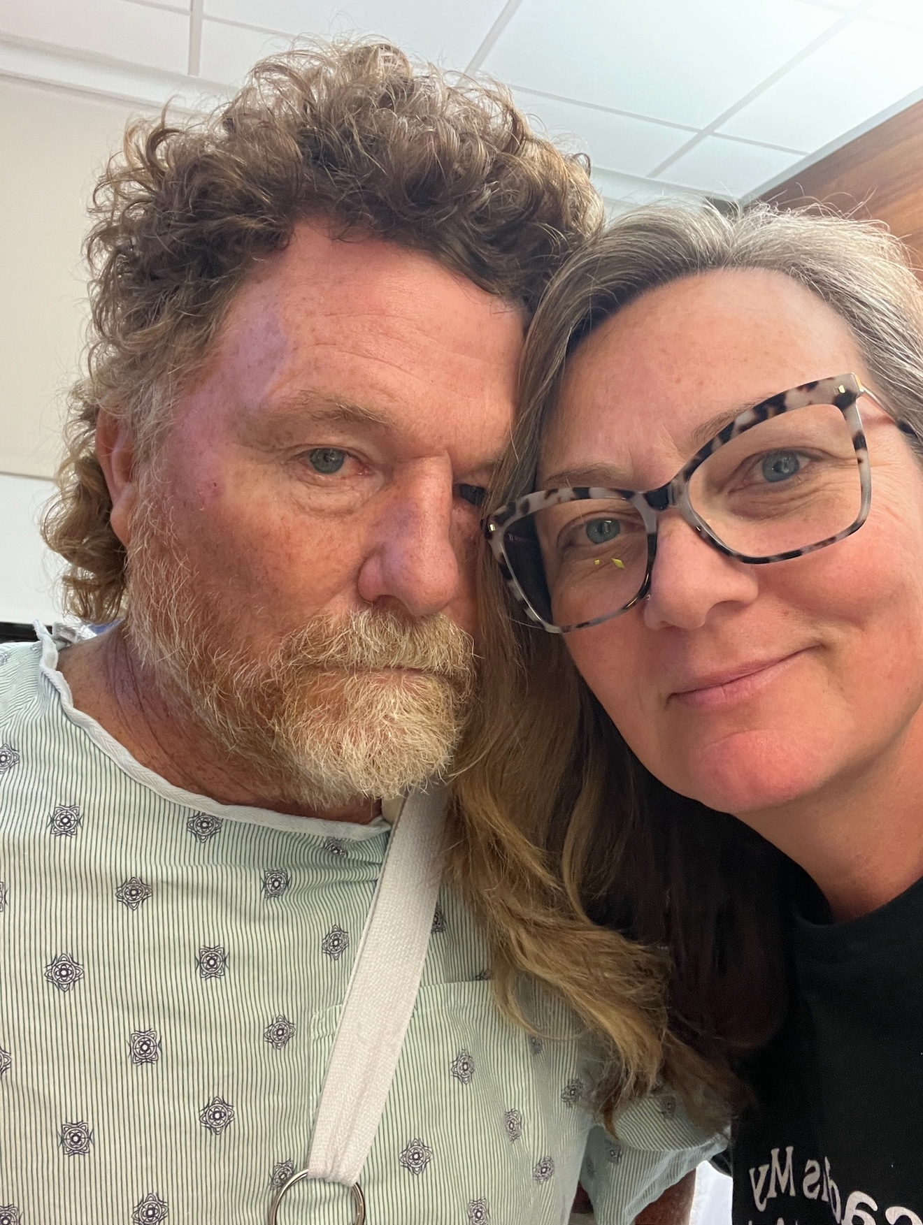 A photo of a husband and wife taking a selfie together indoors.